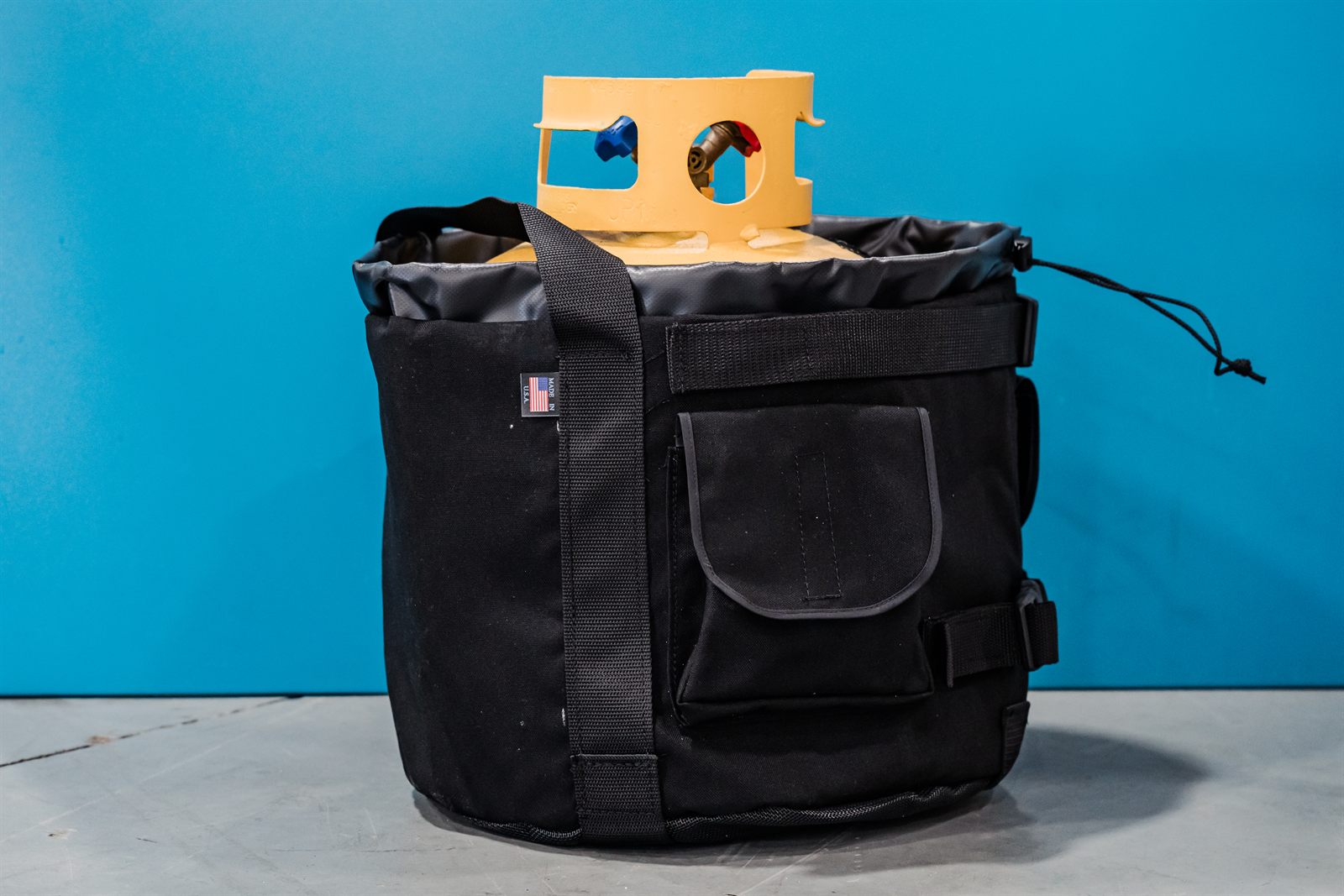 Angled view of the black Tank Cooler showing the drawstring toggle and side compression strap