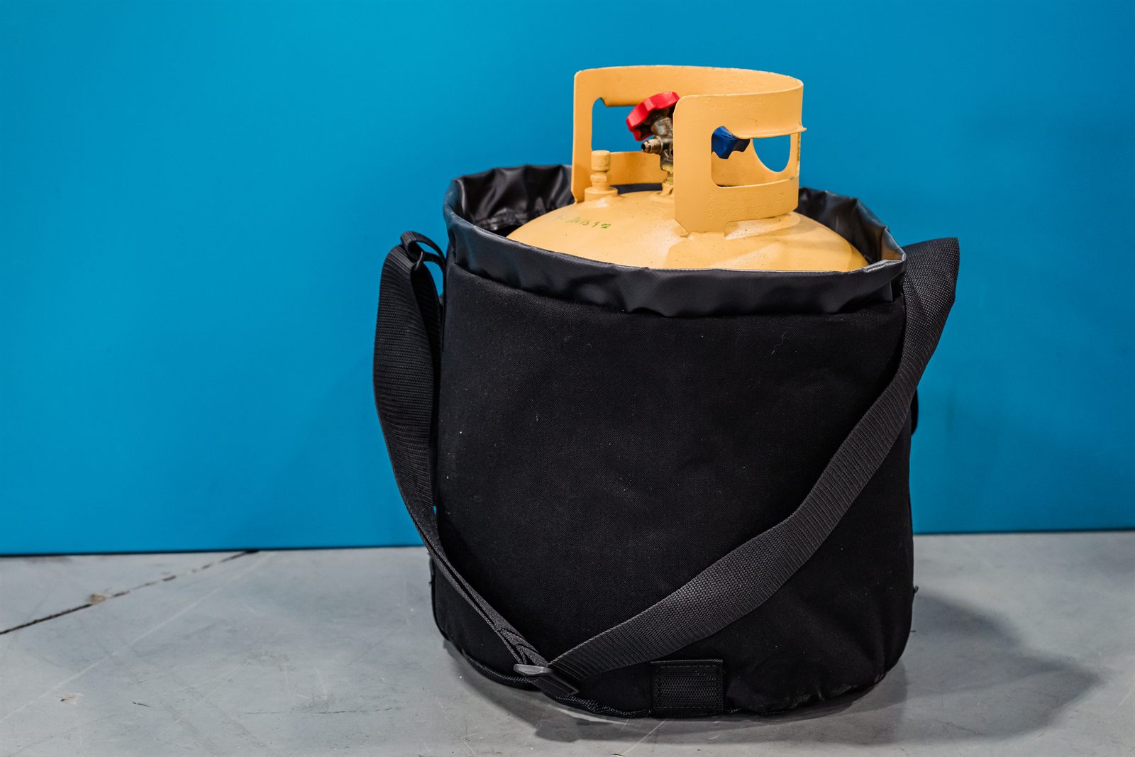 The black Tank Cooler bag holding a yellow refrigerant recovery cylinder, shoulder strap across the front