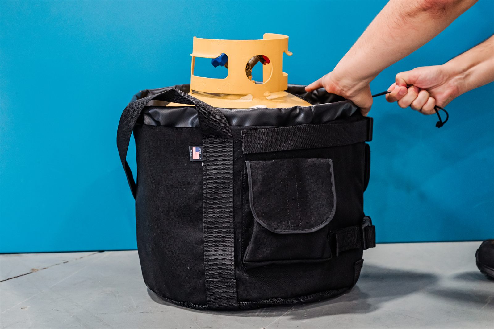 Pulling the drawstring closure tight around the neck of the recovery tank to seal in the cold