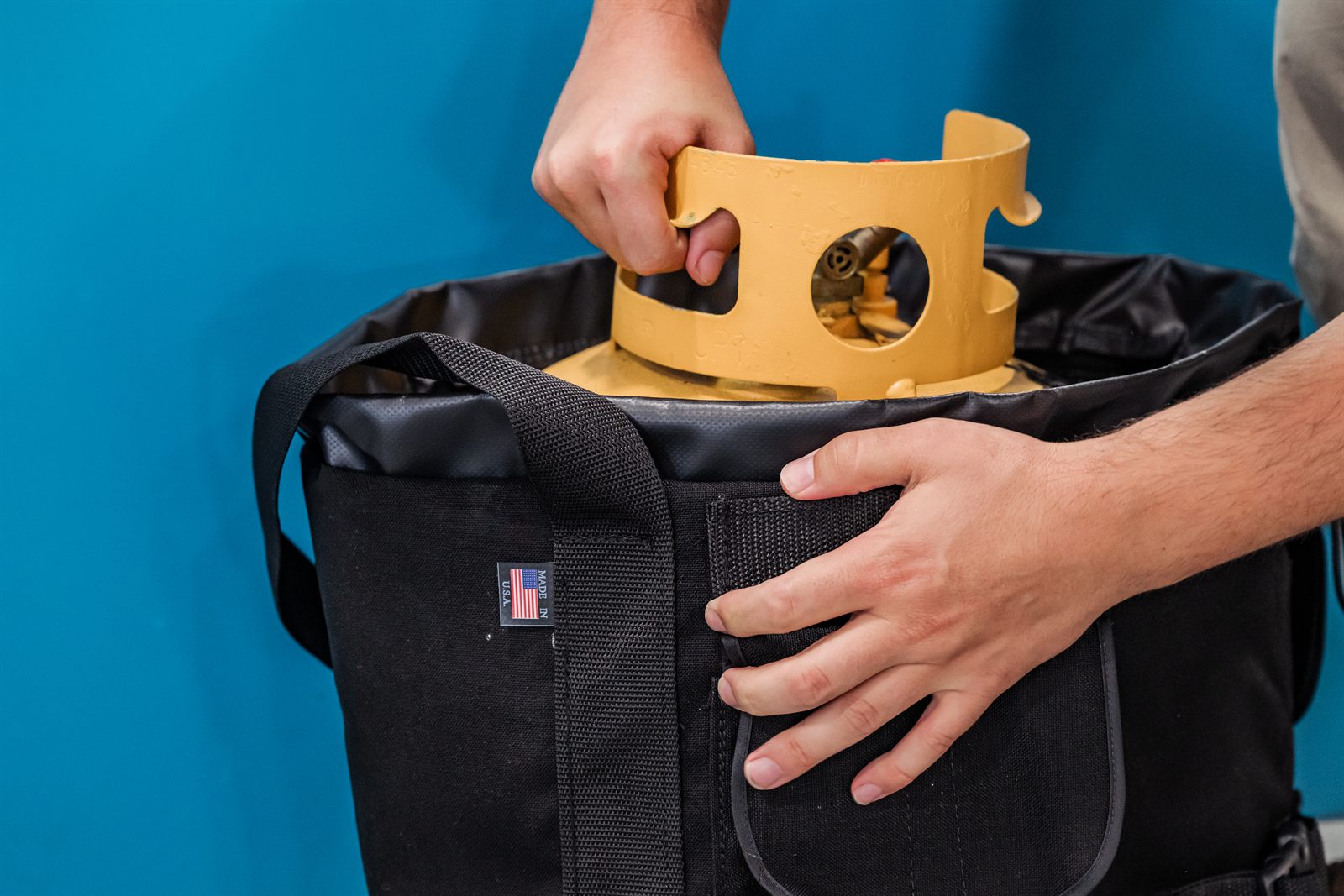 A technician lowering a refrigerant recovery cylinder into the Tank Cooler bag